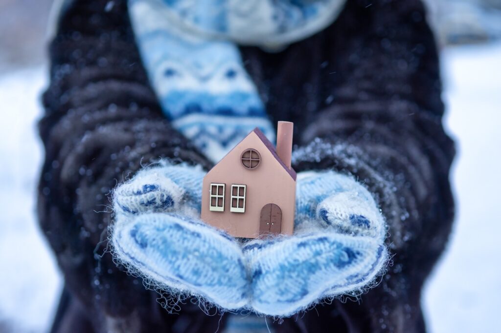 Frau hält kleines Haus mit Schal in der Hand