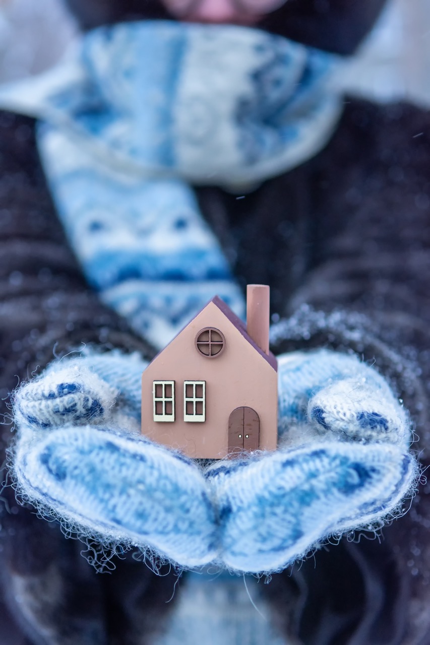Frau hält kleines Haus mit Schal in der Hand