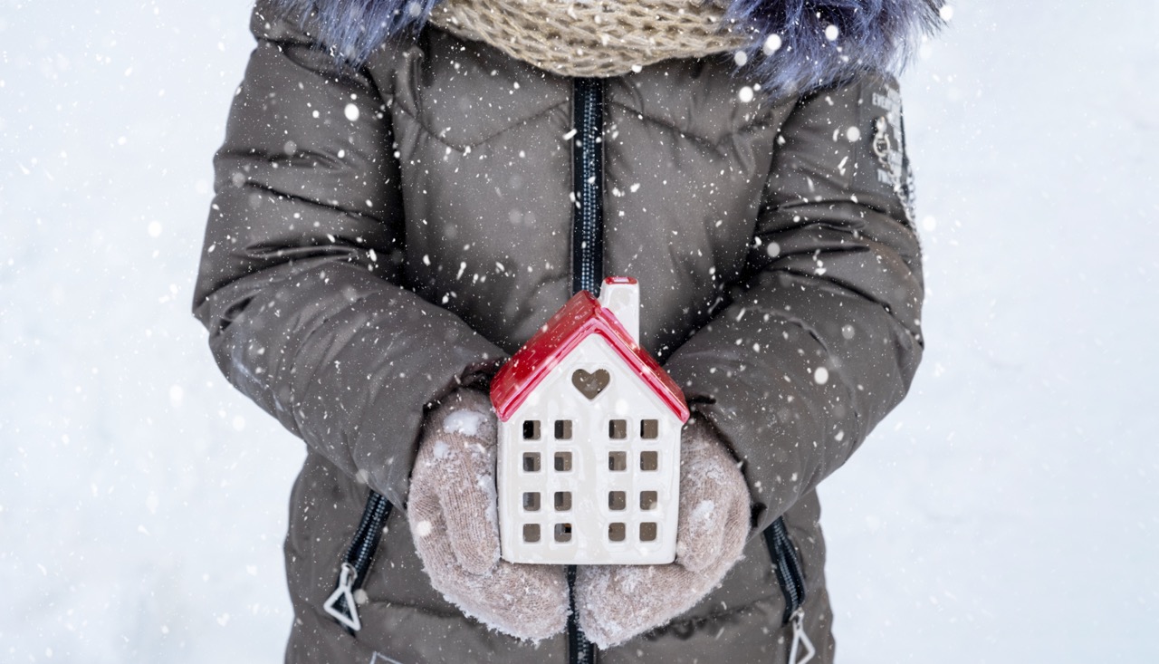 Frau hält kleines Haus mit Schal in der Hand